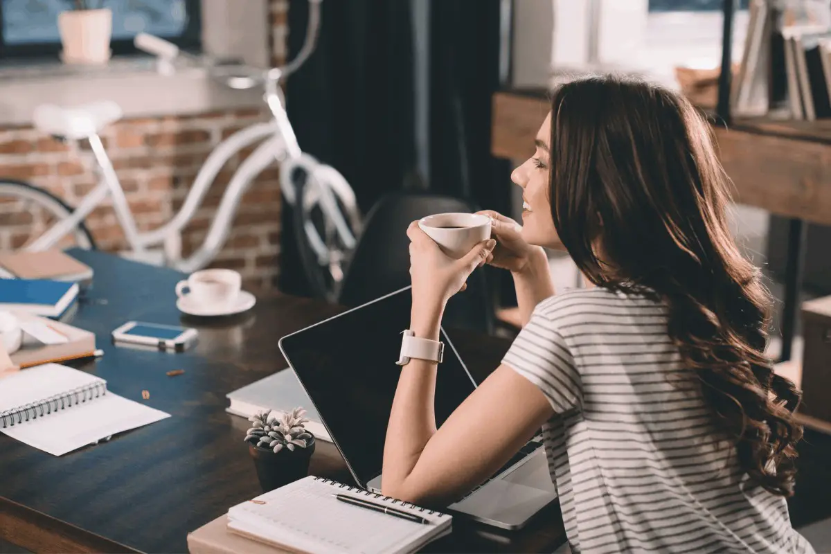 a woman drinking coffee and working on a computer