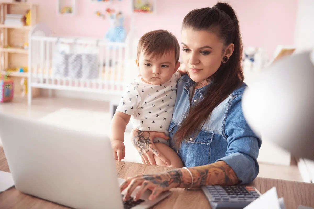a woman holding a child and typing on a laptop