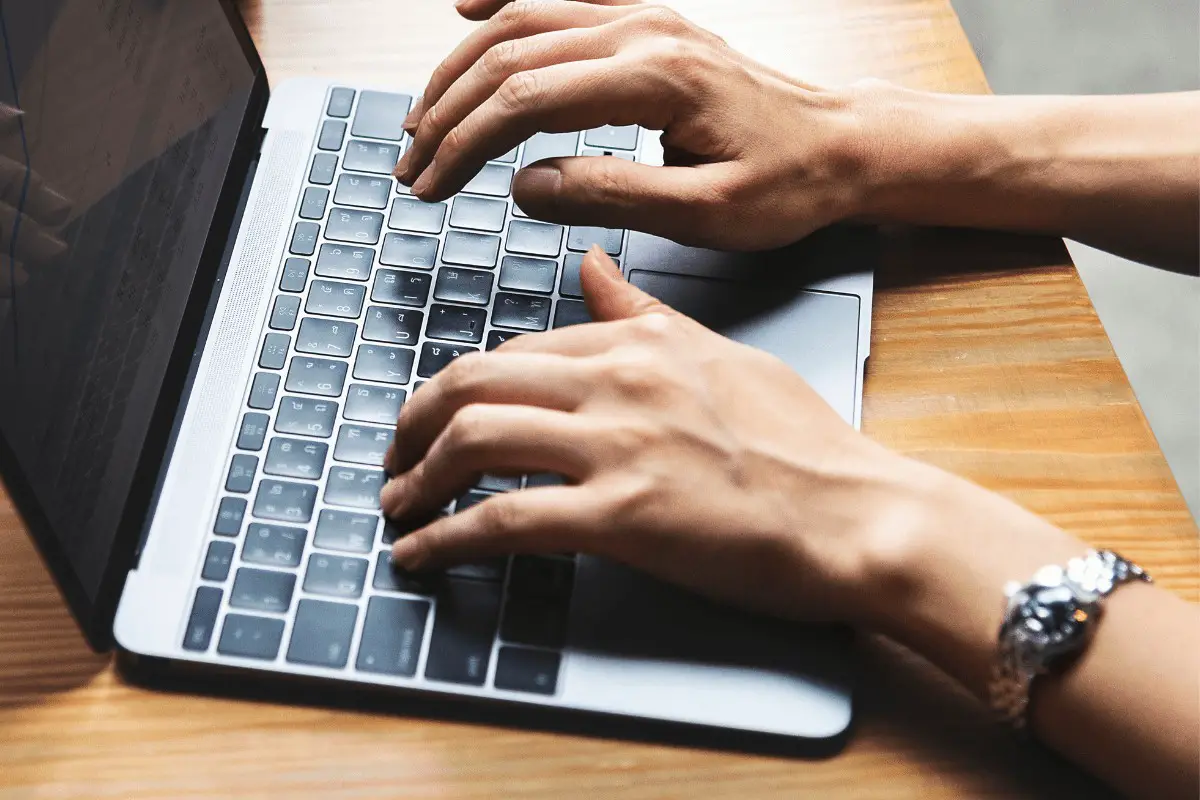 hands typing on a laptop keyboard