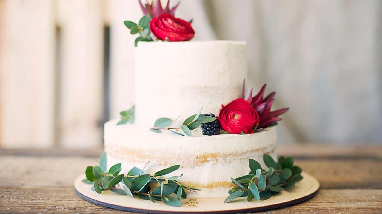 a white cake with multiple tiers decorated with green leaves and pink flowers