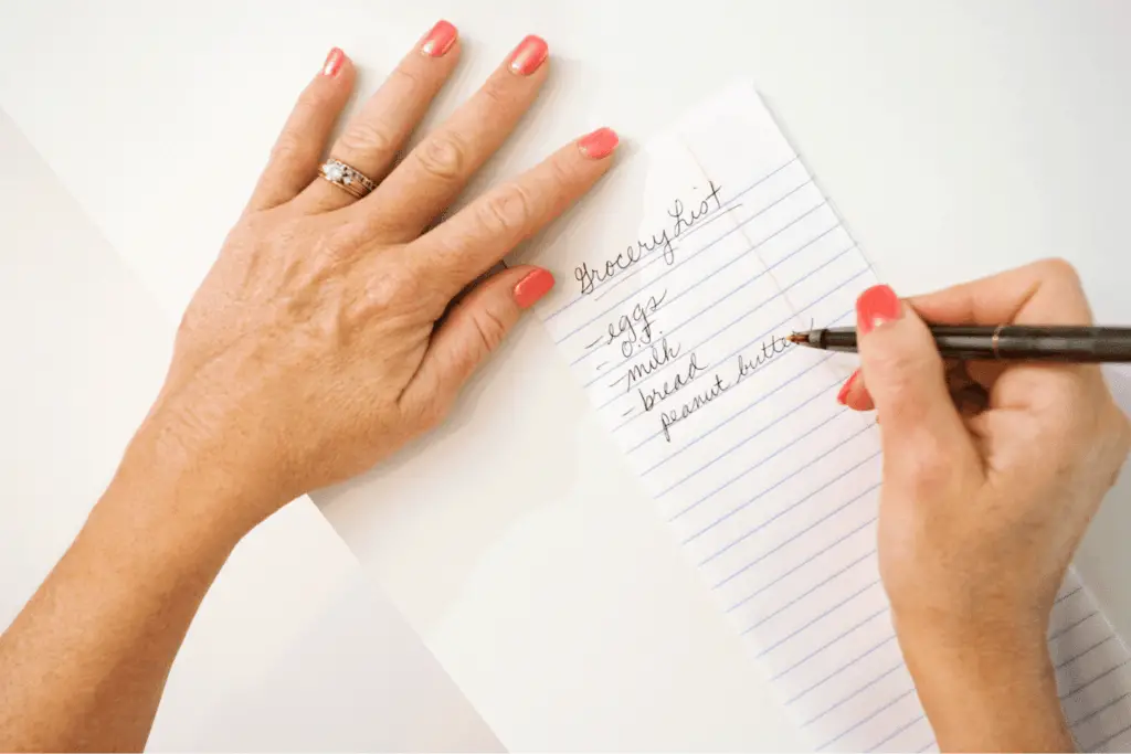 Woman writing grocery list save money by meal planning