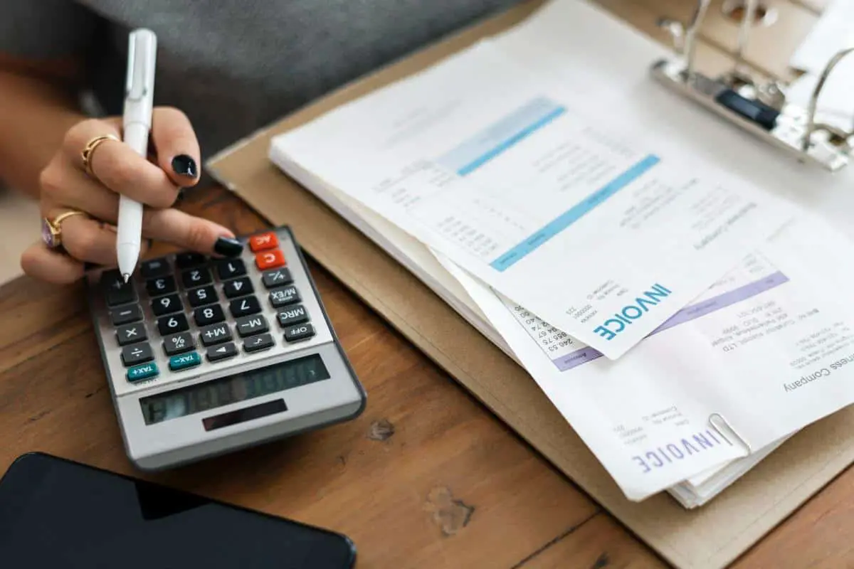 woman typing on a calculator with invoices on the side