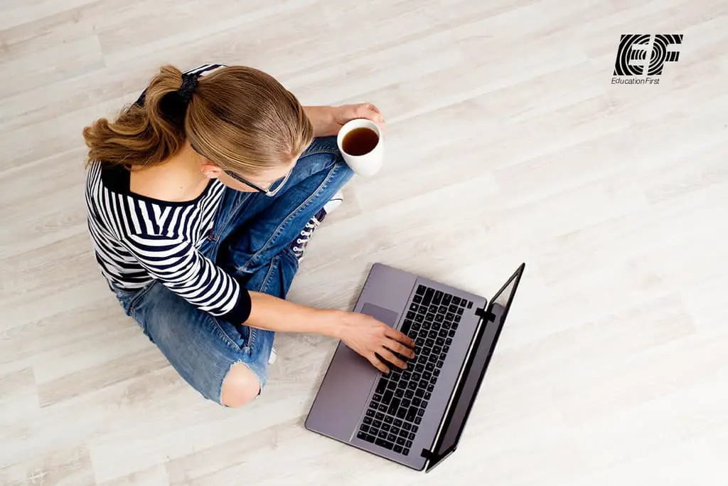 woman using computer holding cup of coffee