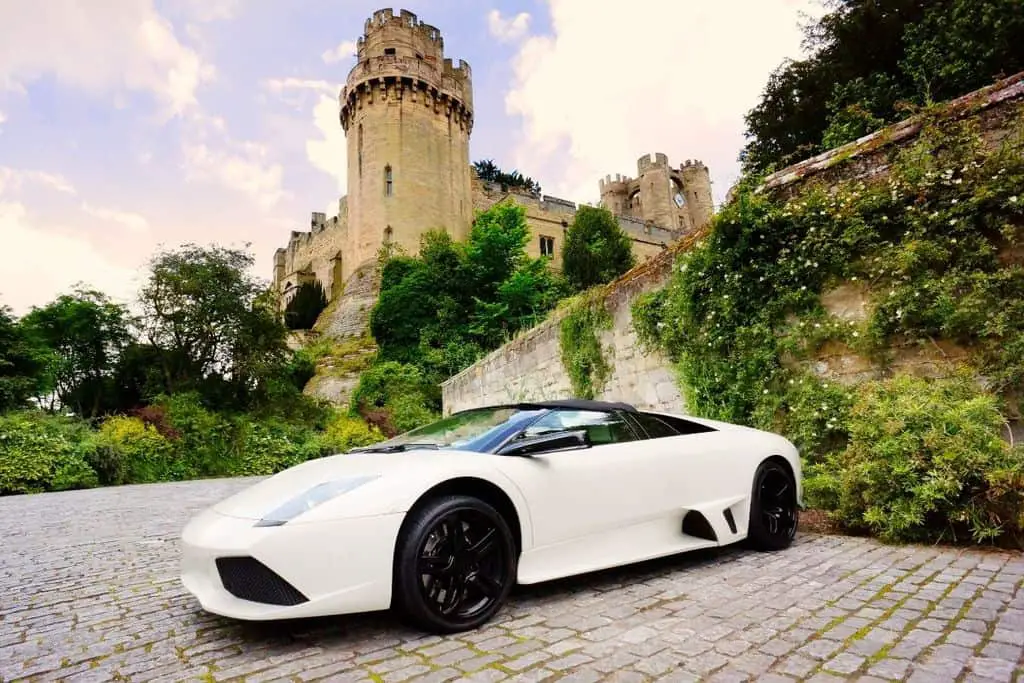 white lamborghini parked in front of castle