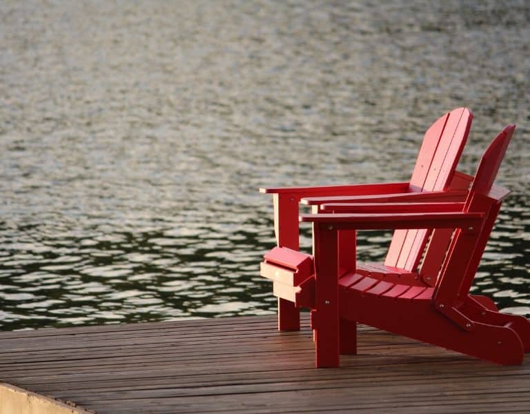 2 red chairs on a dock over water