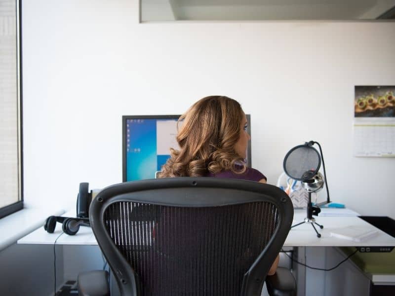 a woman sitting at a desk facing away from the camera