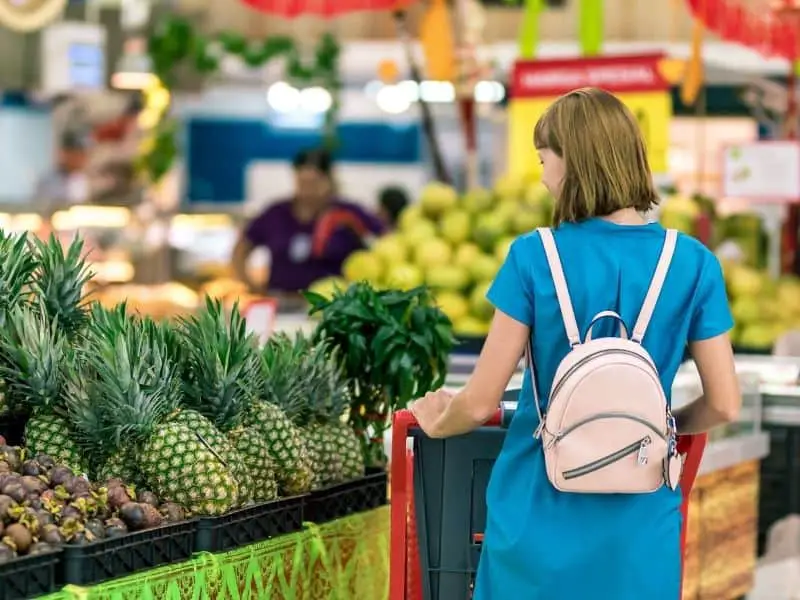 woman pushing a cart in the produce section of a grocery store