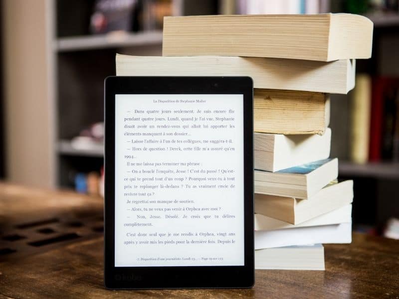 kindle leaning up against a stack of books