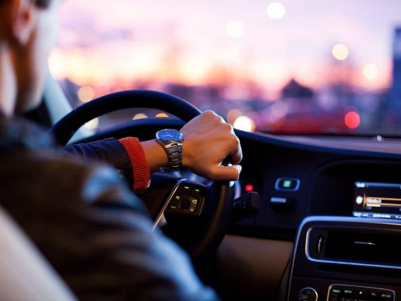 a person driving with hand on the steering wheel