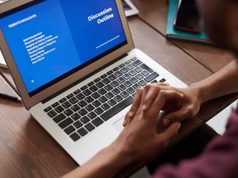 hands clasped in front of a laptop with a blue screen