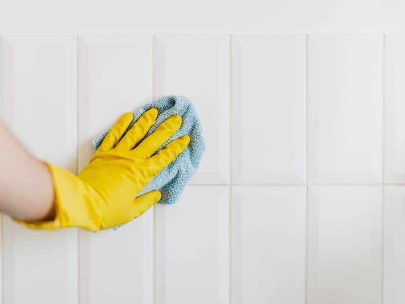 a hand wearing a yellow gloved cleaning a surface with a rag