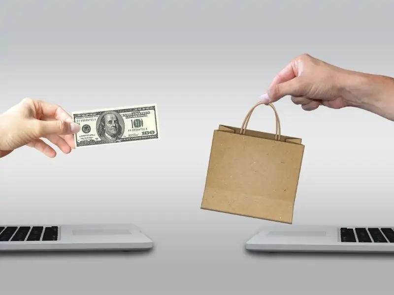 hands coming out of computer screens to exchange a paper bag for money