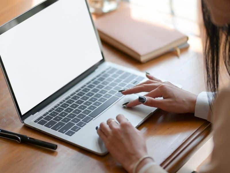 a womand hands typing on a laptop on a desk