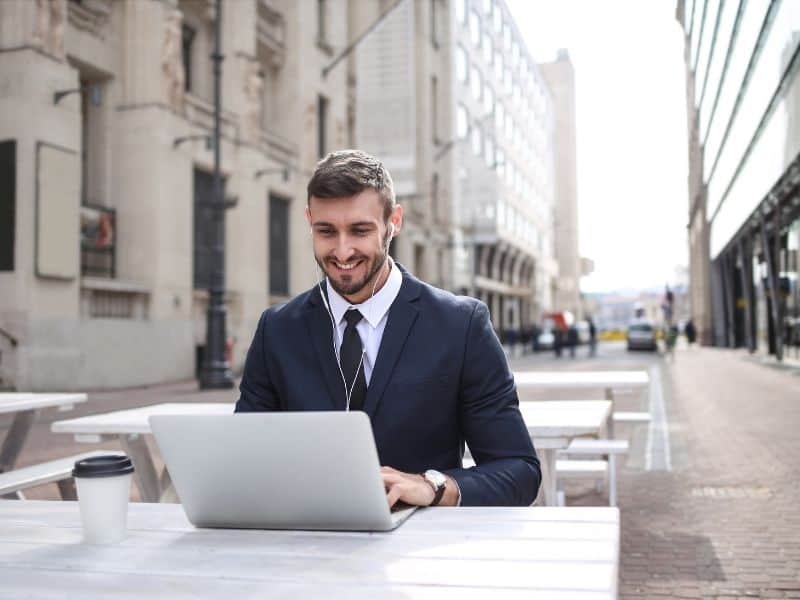 a man in a suit working on a laptop outside