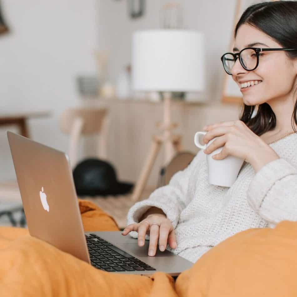 a woman drinking coffe in front of a laptop