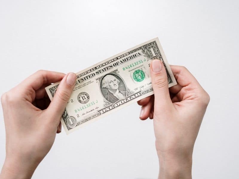 2 hands holding a dollar bill against a white background