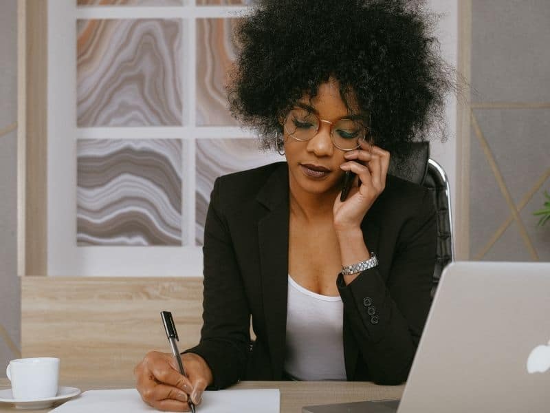 a woman on the phone writing on a desk