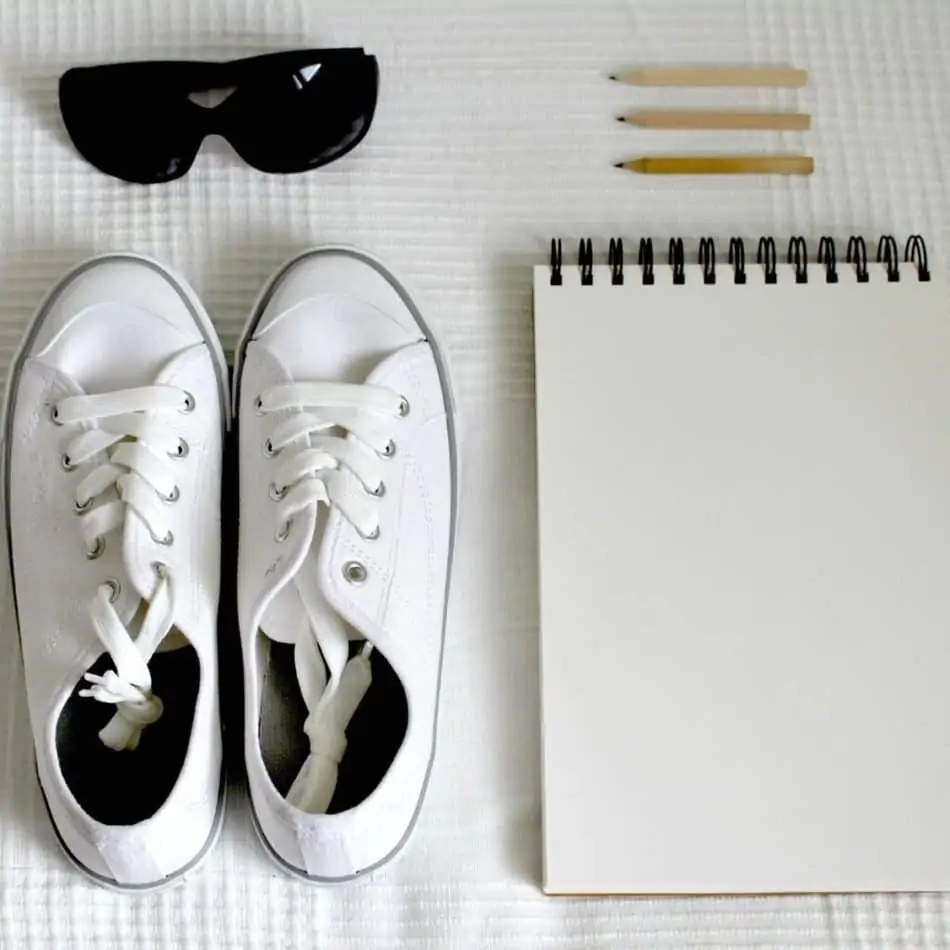 a pair of sneaker next to a notepad and some sunglasses