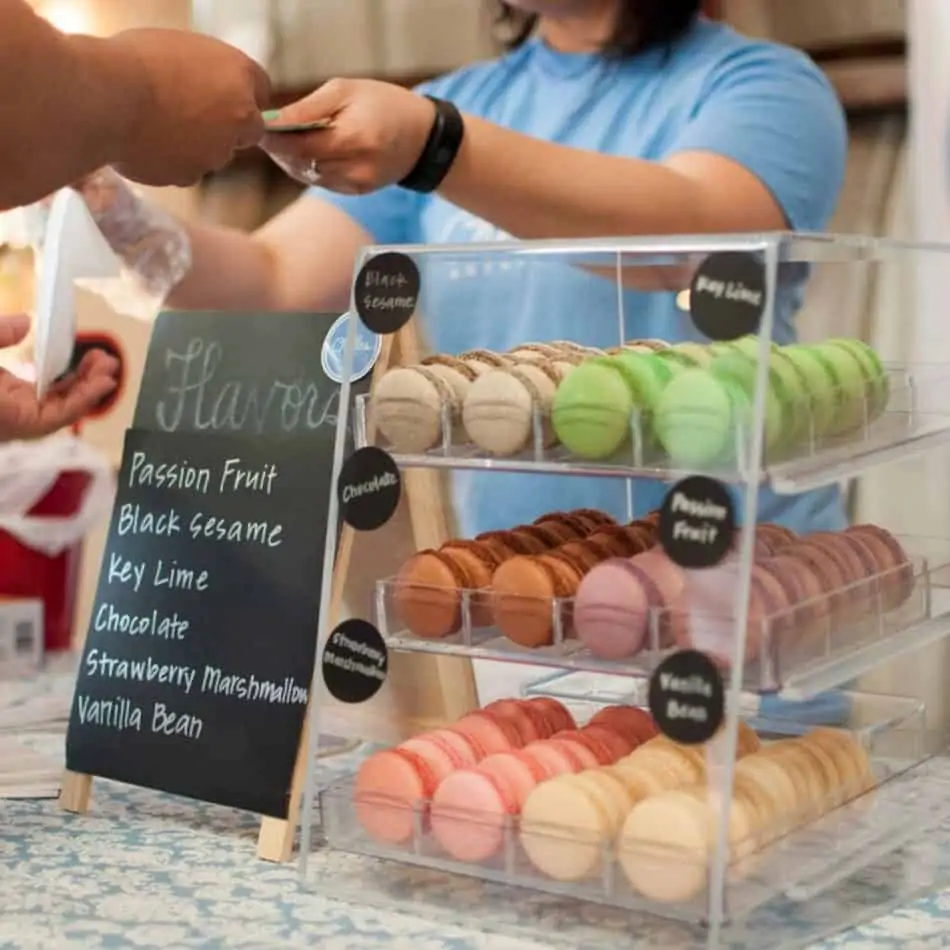macarons in a display case with a sign to the side