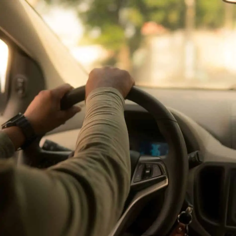 a person driving with hands on the steering wheel