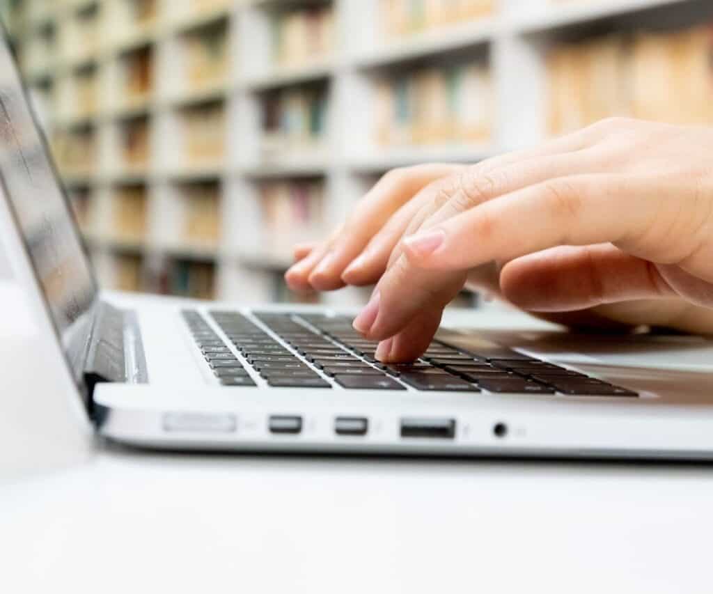 hands typing on a laptop in a library