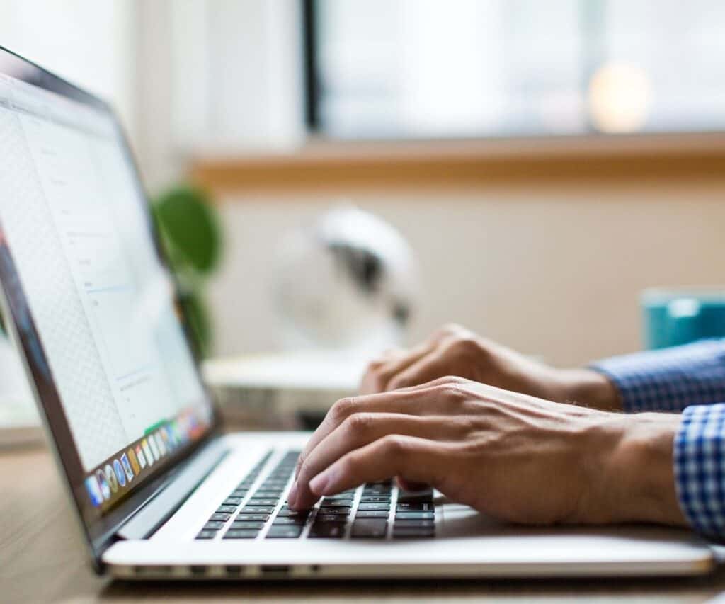 a mans hands typing on a laptop on a table