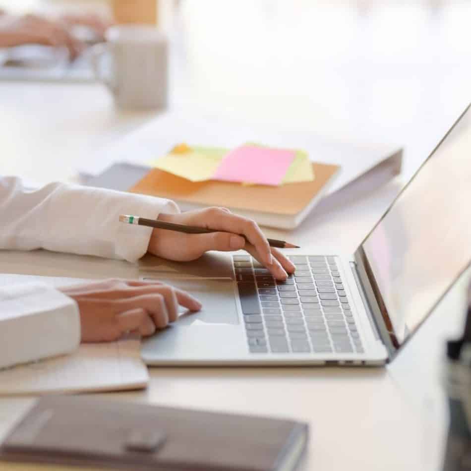 a computer on a desk with hands typing