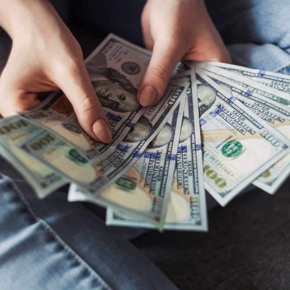 hands fanning out 100 dollar bills