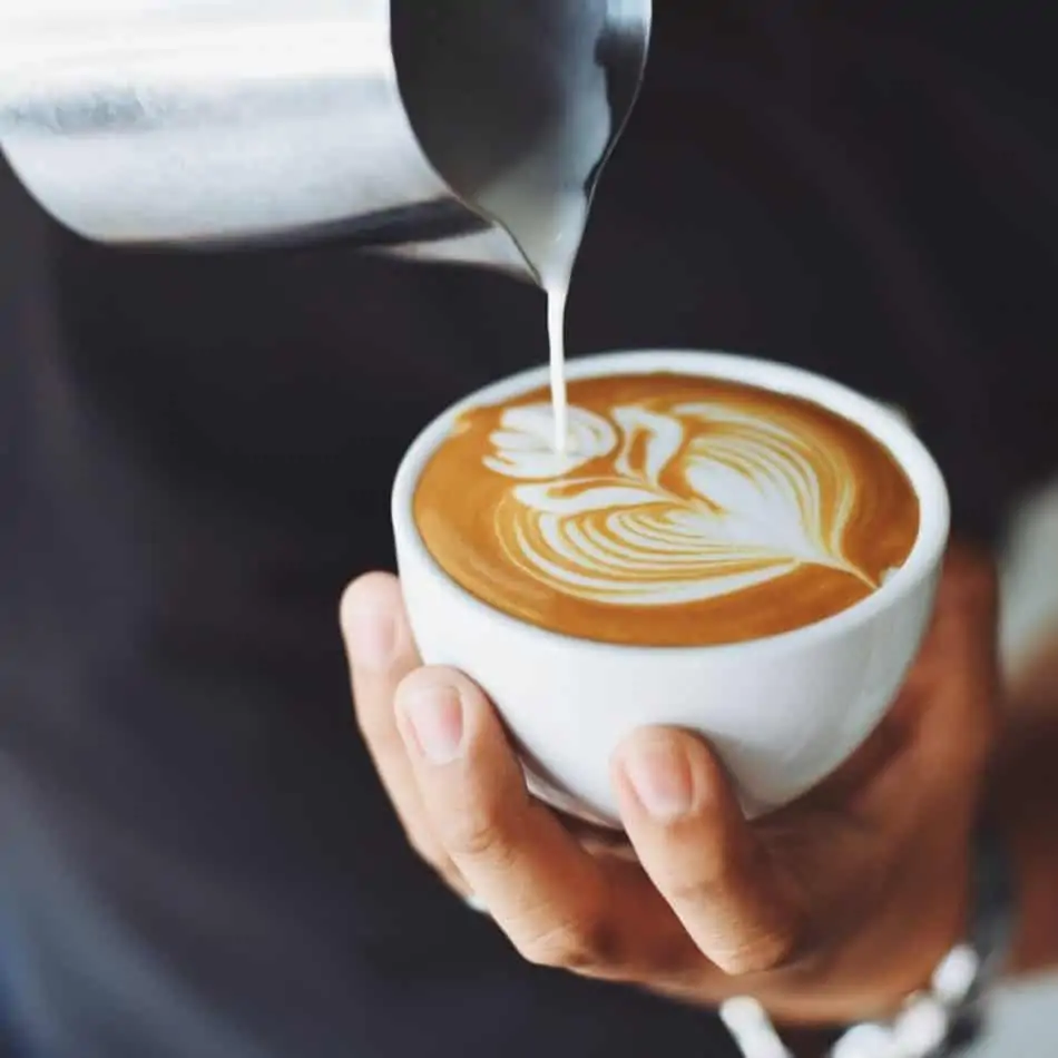 a person pouring a cup of coffee while holding the cup