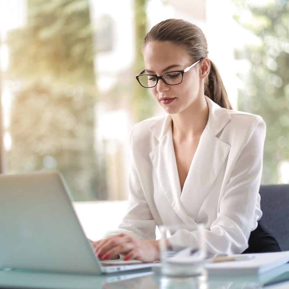 a woman typing on a laptop on a desk