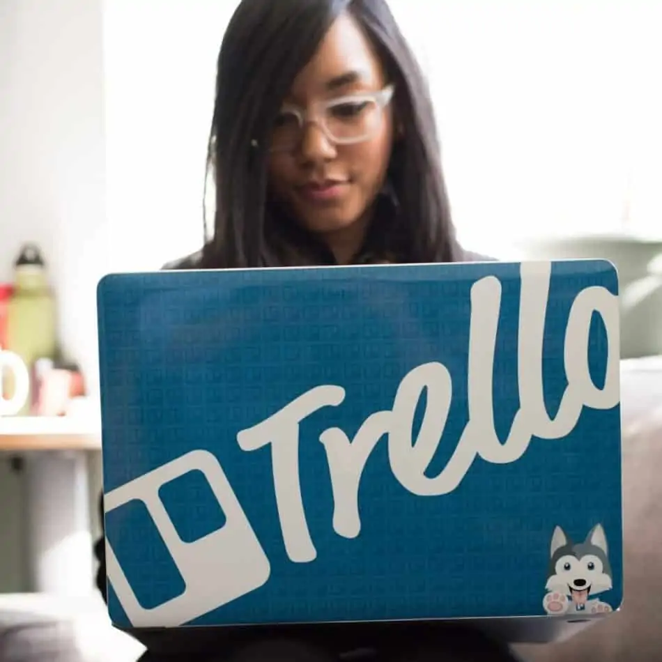 a woman holding a laptop with a "Trello" case
