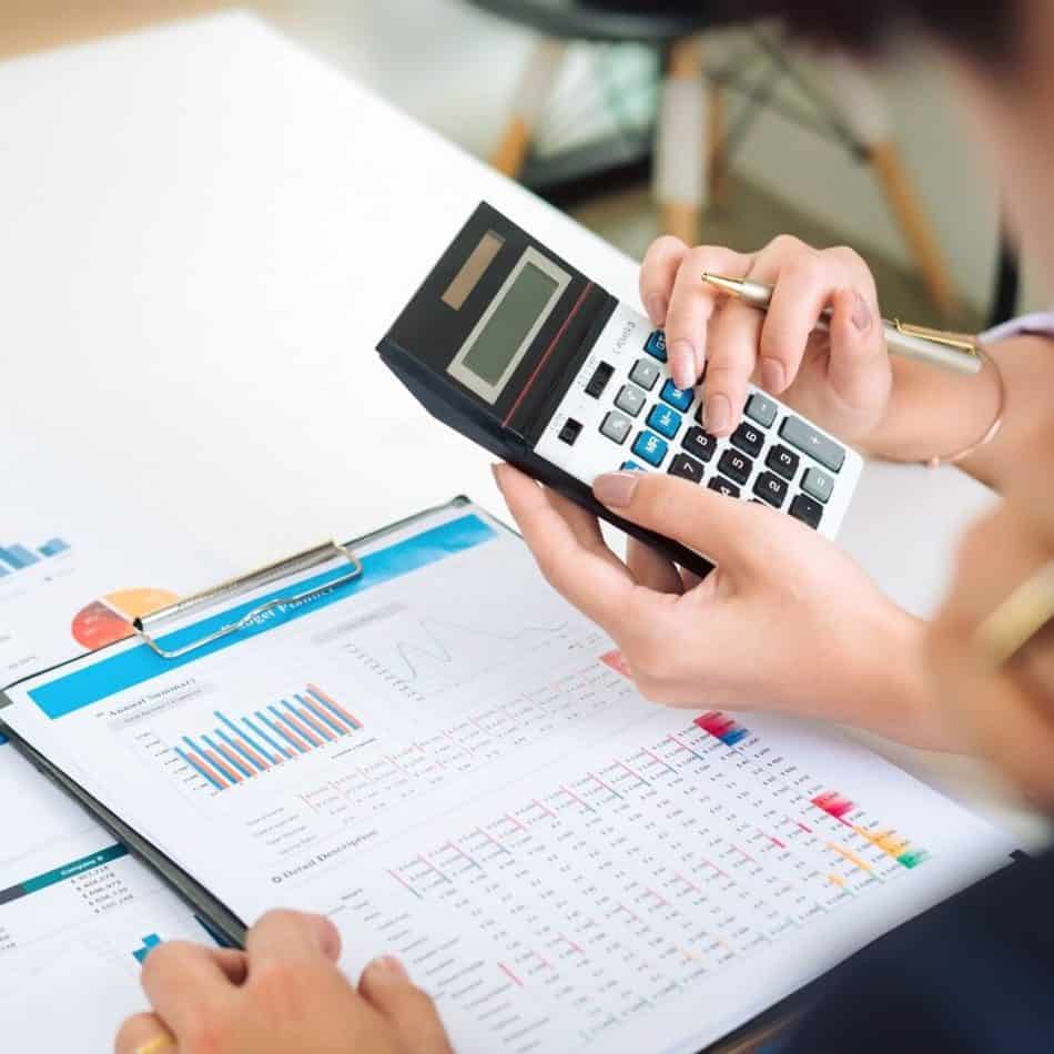 hands typing on a calculator over a notebook