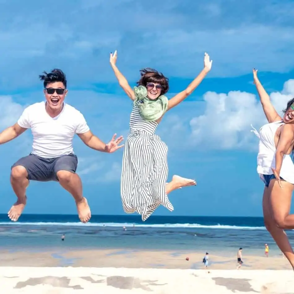 3 people jumping in the air with the ocean in the background