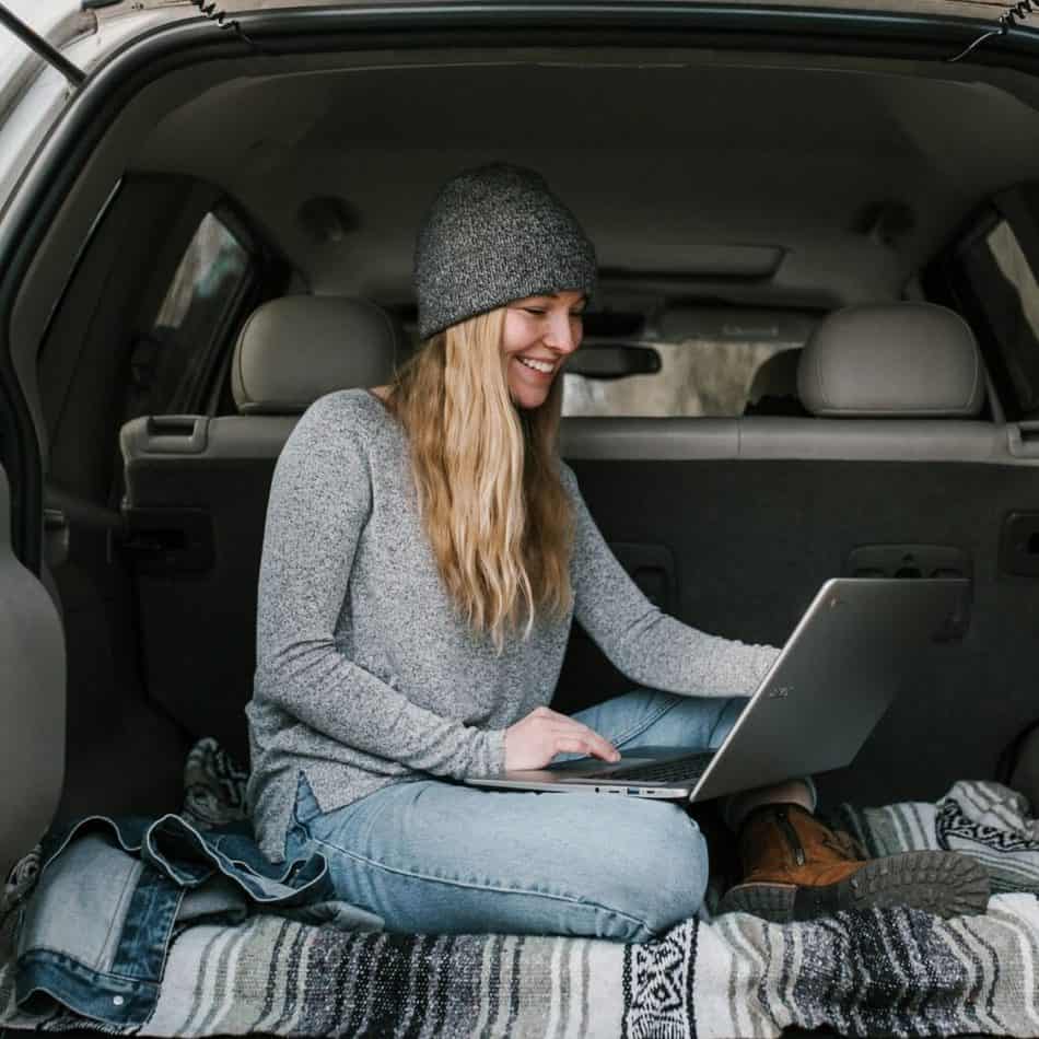 a woman sitting in her truck with a laptop in front of her