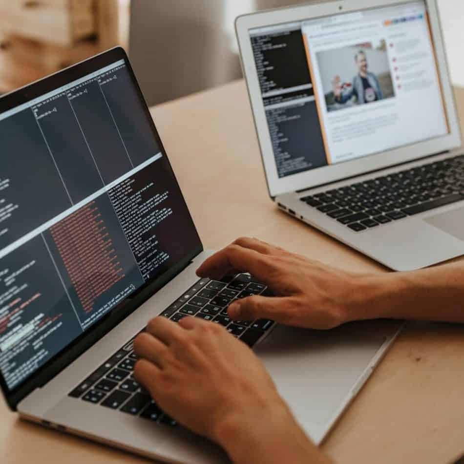 hands typing on a laptop with another laptop in the background